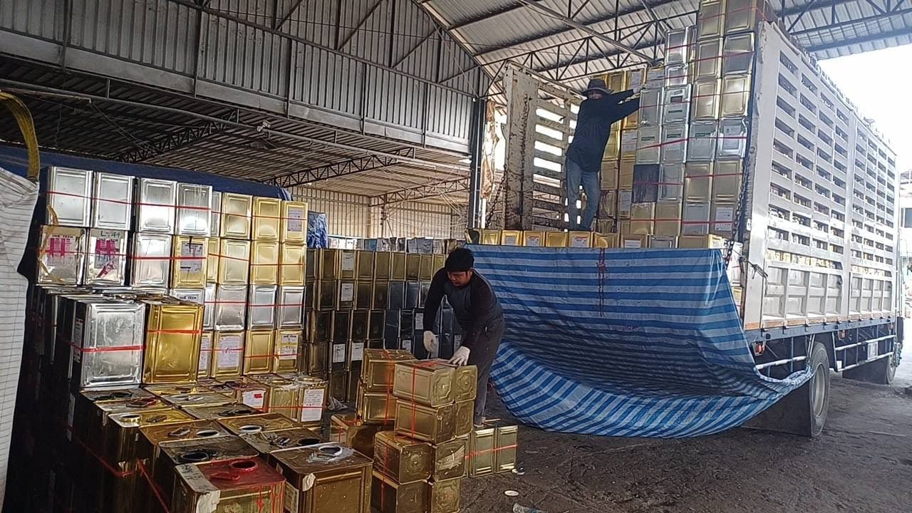 Loading vegetable oil tins onto a truck for container export from Thailand